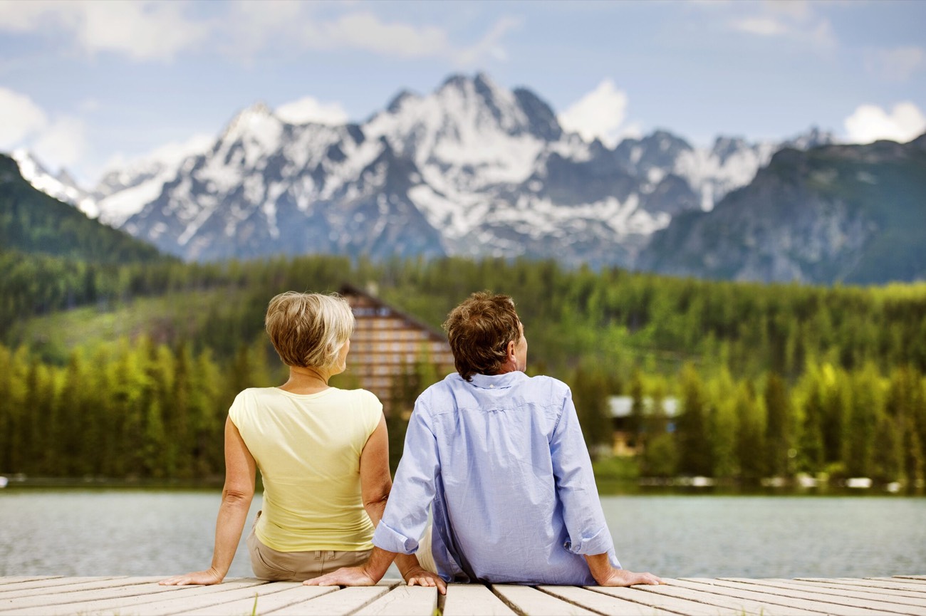 A retired couple holding hands on a lakeside dock